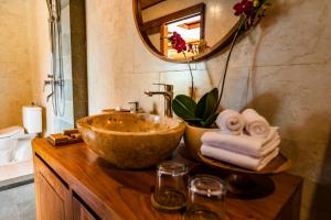 a bathroom with a bowl sink and a mirror at Ellena Resort Tegallalang by Dhananjaya Hospitality in Tampaksiring