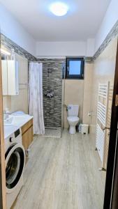 a bathroom with a washing machine and a toilet at Apartament Complex Rezidential Magnolia Bariera Valcii in Craiova