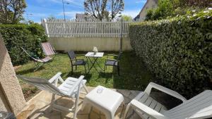 einen Hinterhof mit Stühlen, einem Tisch und einem Zaun in der Unterkunft Studio avec jardin centre ville Cabourg La Roseraie in Cabourg
