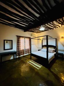 a bedroom with a canopy bed and a window at Villa Kazungu in Ukunda