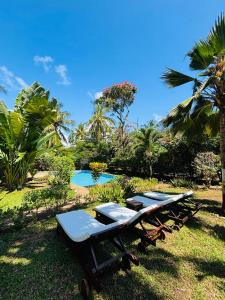 a picnic table and benches in the grass near a pool at Villa Kazungu in Ukunda