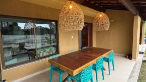een eettafel met blauwe stoelen en kroonluchters bij Refúgio Casa Pitinga in Porto Seguro