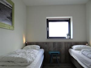2 Betten in einem Zimmer mit einem Fenster und einem Stuhl in der Unterkunft Vakantie appartement Veerse Muze in Kamperland
