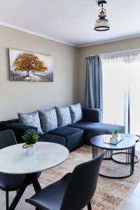 a living room with a blue couch and two tables at Cozy 1-Bed Apartment in Gaborone in Gaborone