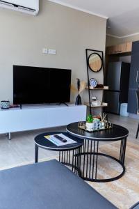 a living room with two tables and a flat screen tv at Cozy 1-Bed Apartment in Gaborone in Gaborone +11 photos
