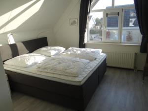 a bed with white sheets and pillows in a room with a window at Vakantievilla Noordzee in Kamperland +30 photos