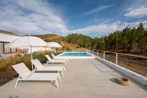 a patio with white lounge chairs and a swimming pool at Monte de Torquines - Casa de Campo com piscina em Odemira in Odemira