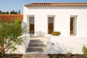 a white house with stairs and a tree at Monte de Torquines - Casa de Campo com piscina em Odemira in Odemira