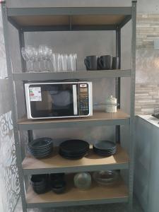 eine Mikrowelle auf einem Regal mit Tellern und Gläsern in der Unterkunft El Kamaruco Hostel in El Chalten