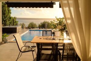 eine Terrasse mit Tisch und Stühlen und einem Pool in der Unterkunft Stunning seaview Villa Katharina in Šarić
