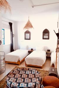 two beds in a room with white walls at Olas Surf Camp in Imsouane