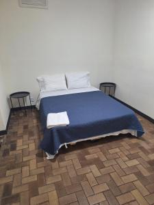 a bed with a blue blanket and two pillows at Luca hostel in San José +9 photos
