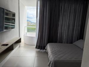 een slaapkamer met een bed, een bad en een raam bij Apartamento con Jacuzzi vista al mar in Santa Marta +8 foto's
