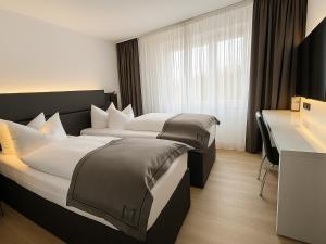 a hotel room with two beds and a desk at DORMERO Hotel Weimar in Weimar