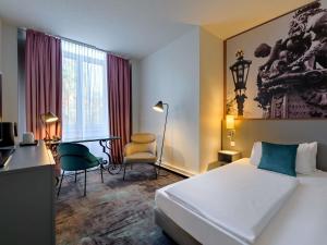 a hotel room with a bed and a desk and chair at Mercure Hotel Hannover City in Hannover +171 photos