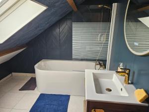 a bathroom with a white tub and a sink at Maison Sérénité in Lailly-en-Val