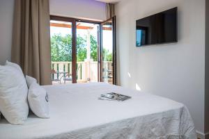 a bedroom with a white bed with a television on the wall at Midnight Serenity in Čilipi +121 photos
