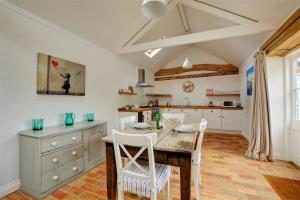 eine Küche mit einem Holztisch und weißen Stühlen in der Unterkunft Simons Barn in Langham + 2 Fotos