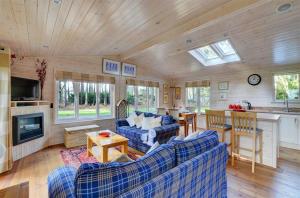 a living room with blue couches and a kitchen at Milliners Lodge in Kelling