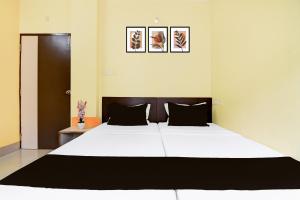een slaapkamer met een groot wit bed met zwarte kussens bij Hotel O Ankita Lodge in Siliguri