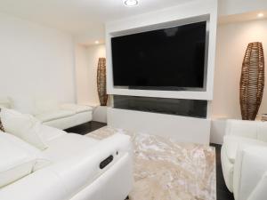 a living room with white furniture and a flat screen tv at Mellings Place in Carnforth