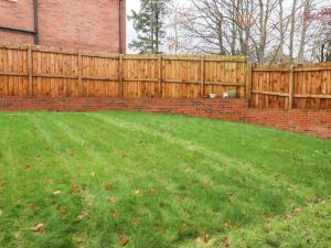 a backyard with a fence and a green lawn at Mellings Place in Carnforth