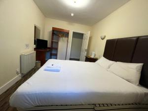 a bedroom with a large white bed with a black headboard at Lochway Hotel in Dumbarton +10 photos