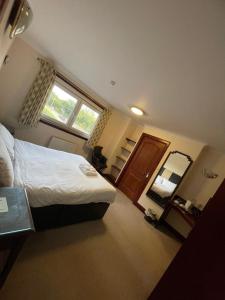Un dormitorio con una cama y un espejo grande. en Lochway Hotel, en Dumbarton