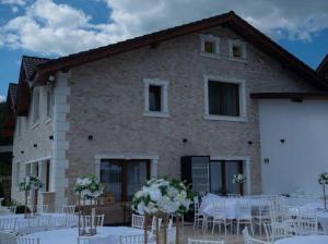 un edificio con mesas y sillas blancas delante de él en Pensiunea Graniti, en Lunca