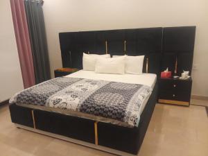 a bedroom with a large bed with a black headboard at Airport Gateway Guesthouse in Rawalpindi