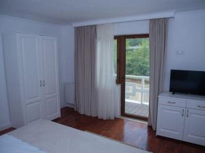 Un dormitorio con una cama y un televisor y un balcón. en Pensiunea Graniti, en Lunca