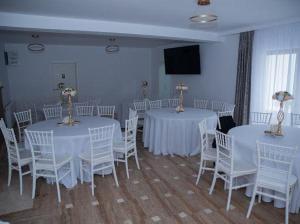 Un salón de banquetes con mesas y sillas blancas. en Pensiunea Graniti, en Lunca 2 fotos más