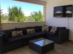 een woonkamer met een bank en een groot raam bij Family-friendly apartments with swimming pool Dvornica, Rogoznica - 11470 in Rogoznica