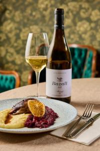 a glass of white wine next to a plate of food at Icce Borbirtok - Wine, Dine & Rest in Monoszló