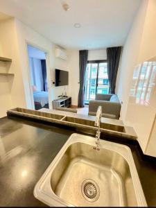 a kitchen with a sink and a living room at The Central Escape Phuket in Ban Rangeng