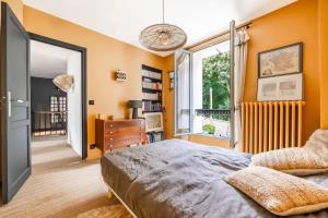 een slaapkamer met oranje muren en een bed en een raam bij House, garden, Eiffel Tower, Palace of Versailles in Sèvres