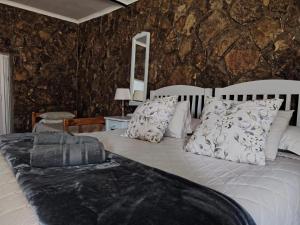 a bedroom with a large bed with a stone wall at Uitzicht Private Nature Reserve and Lodge in Fouriesburg