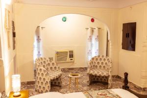 斋浦尔Ancestral Abode - A Boutique Homestay的有两把椅子和一张桌子的客厅