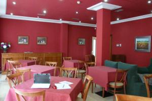 un restaurante con paredes y mesas rojas y un ordenador portátil en Idh Angel, en Oviedo