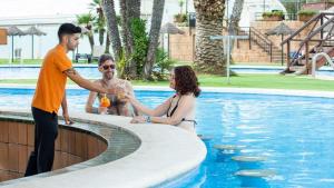 Dos hombres y una mujer de pie junto a una piscina en Evenia Olympic Palace, en Lloret de Mar