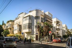 Un gran edificio blanco con coches aparcados delante. en Modern Studio Apt with Balcony by Sea N Rent, en Tel Aviv