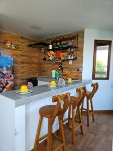 a kitchen with a counter with four stools at a bar at FLATS SHALON - MORRO DE SÃO PAULO in Morro de São Paulo +60 photos