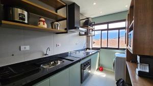 a kitchen with a sink and a stove top oven at Apartamento com 1 suíte, 1 lavabo, 1 vaga a 70m da Praia in Praia Grande +17 photos