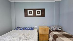 a bedroom with two beds and a picture on the wall at Apartamento com 1 suíte, 1 lavabo, 1 vaga a 70m da Praia in Praia Grande