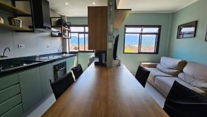 a kitchen and living room with a couch and a table at Apartamento com 1 suíte, 1 lavabo, 1 vaga a 70m da Praia in Praia Grande