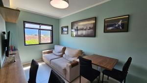 a living room with a couch and a table at Apartamento com 1 suíte, 1 lavabo, 1 vaga a 70m da Praia in Praia Grande