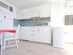 eine weiße Küche mit einem Tisch und einem Kühlschrank in der Unterkunft Los Molinos 503 in San Bartolomé de Tirajana