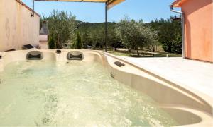 eine Whirlpool-Badewanne in einem Garten mit Bäumen in der Unterkunft Holiday house with a parking space Mundanije, Rab - 18889 in Rab