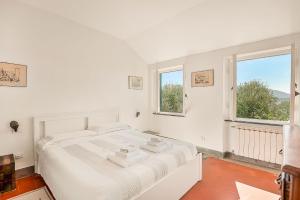 a white bedroom with a bed and two windows at La dimora dell'artista sea view free parking in San Terenzo