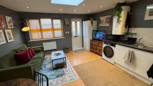 ein Wohnzimmer mit einem grünen Sofa und einem Fernseher in der Unterkunft Watford High Street apartment with kitchen & sofa bed in Watford